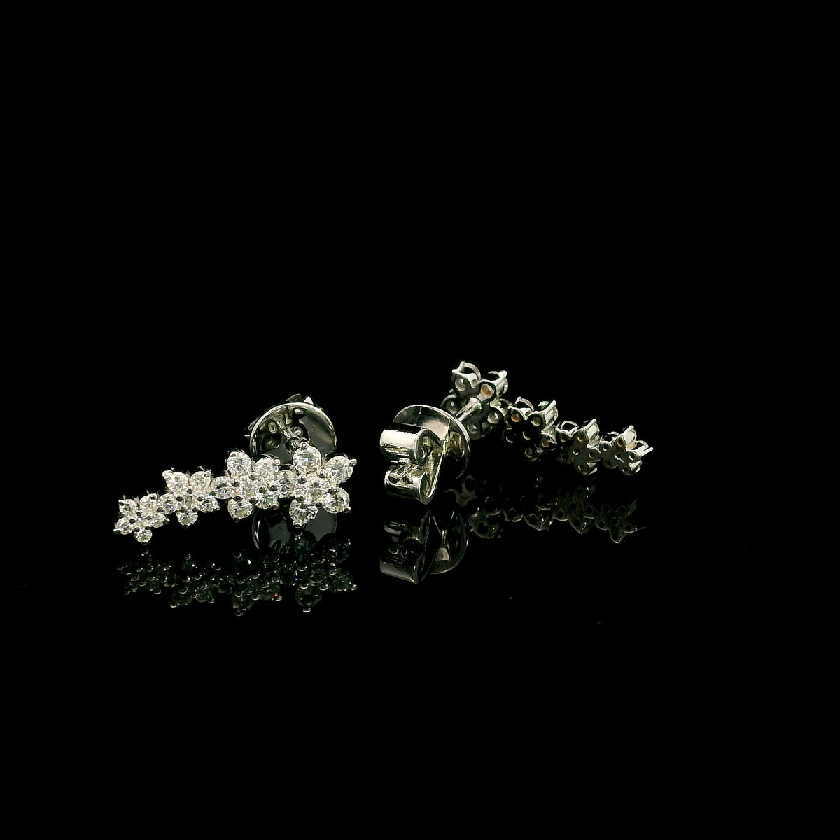 Diamond floral ear climber earrings in 18K white gold with graduating round diamond flower clusters designed to follow the ear.