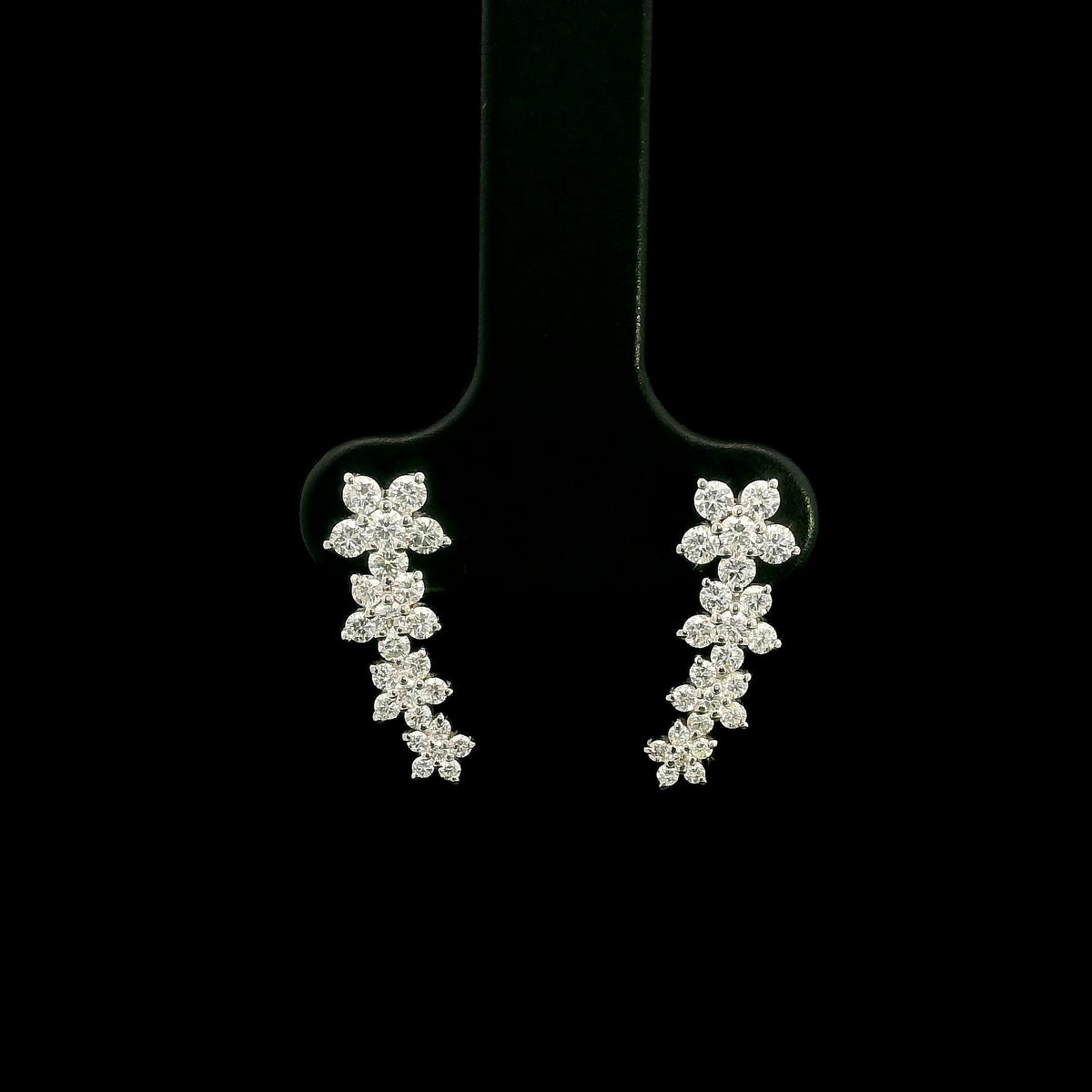Diamond floral ear climber earrings in 18K white gold with graduating round diamond flower clusters designed to follow the ear.