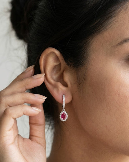 Ruby and diamond drop earrings in 18K white gold with oval ruby centres and diamond halos