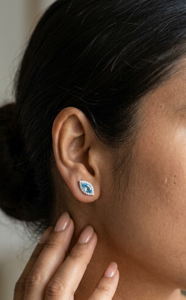 18K white gold blue topaz and diamond halo stud earrings featuring marquise-shaped blue topaz gemstones surrounded by round diamonds in an eye-shaped design.