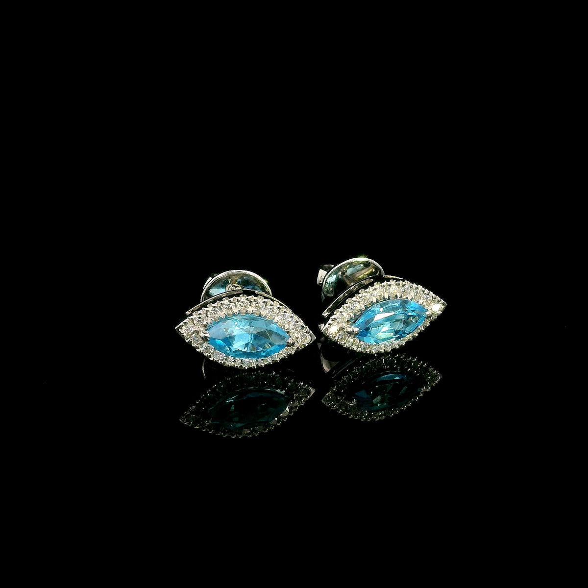 18K white gold blue topaz and diamond halo stud earrings featuring marquise-shaped blue topaz gemstones surrounded by round diamonds in an eye-shaped design.
