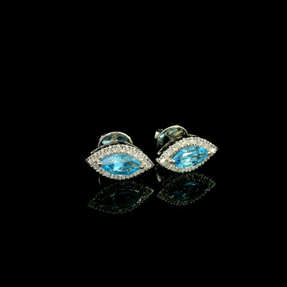 18K white gold blue topaz and diamond halo stud earrings featuring marquise-shaped blue topaz gemstones surrounded by round diamonds in an eye-shaped design.