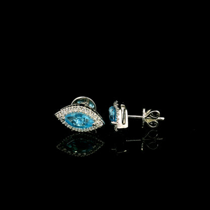 18K white gold blue topaz and diamond halo stud earrings featuring marquise-shaped blue topaz gemstones surrounded by round diamonds in an eye-shaped design.