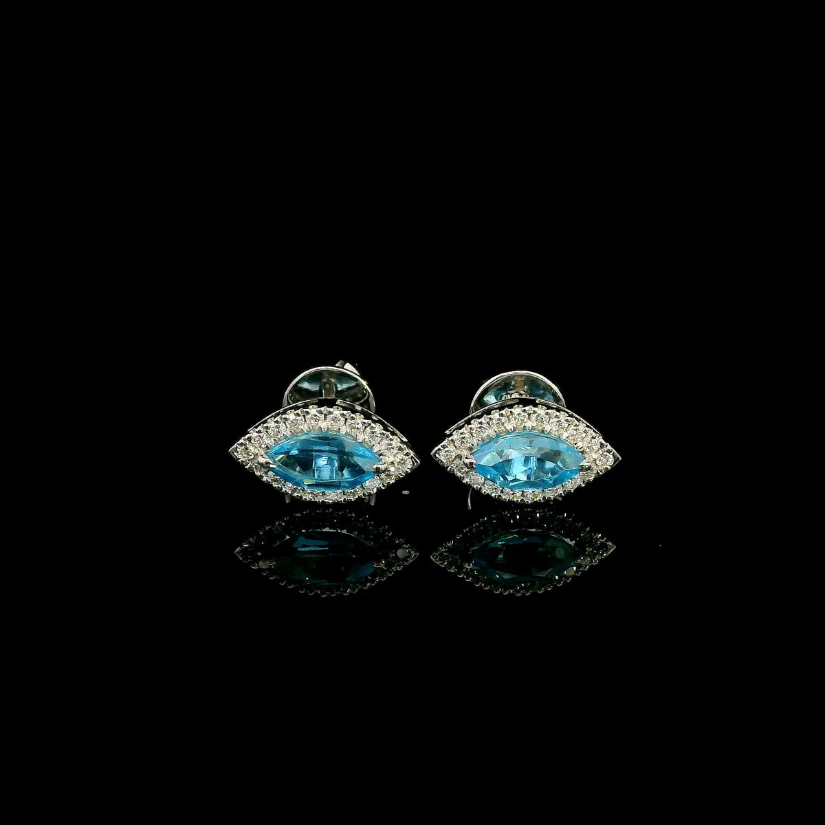 18K white gold blue topaz and diamond halo stud earrings featuring marquise-shaped blue topaz gemstones surrounded by round diamonds in an eye-shaped design.