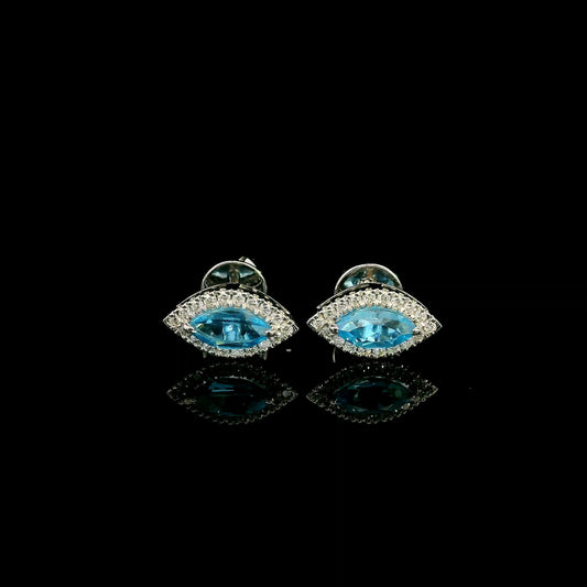 18K white gold blue topaz and diamond halo stud earrings featuring marquise-shaped blue topaz gemstones surrounded by round diamonds in an eye-shaped design.