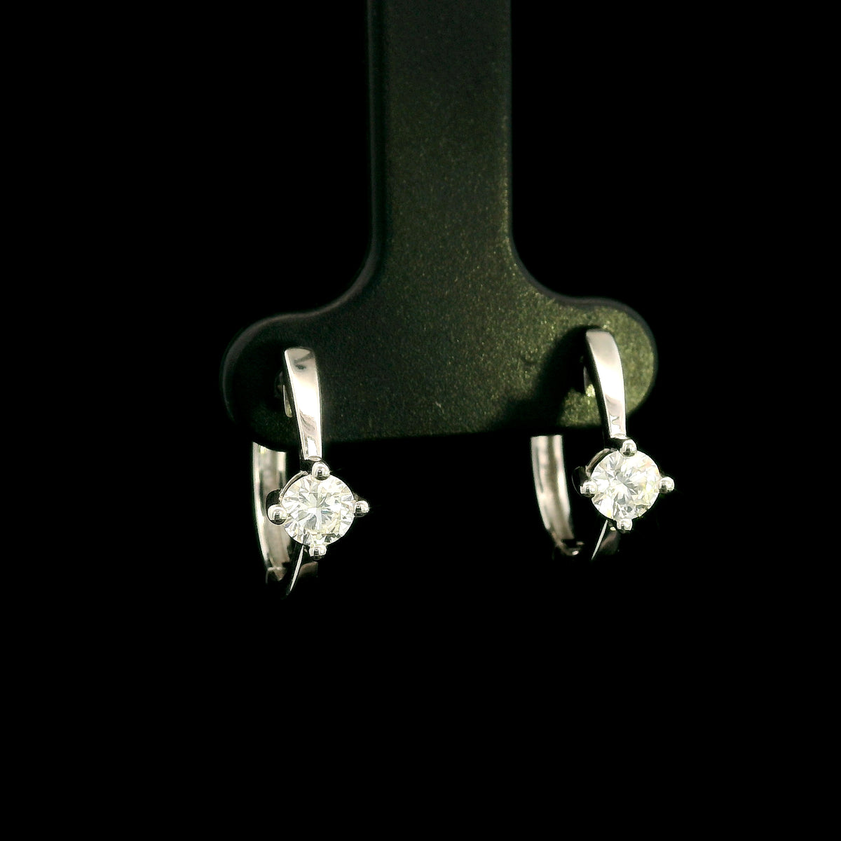 18K white gold huggie hoop earrings featuring a round diamond in a four-prong setting on each polished hoop.
