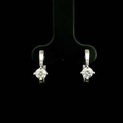 18K white gold huggie hoop earrings featuring a round diamond in a four-prong setting on each polished hoop.