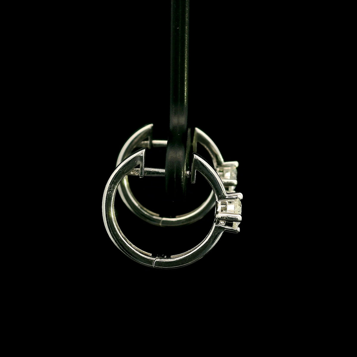 18K white gold huggie hoop earrings featuring a round diamond in a four-prong setting on each polished hoop.