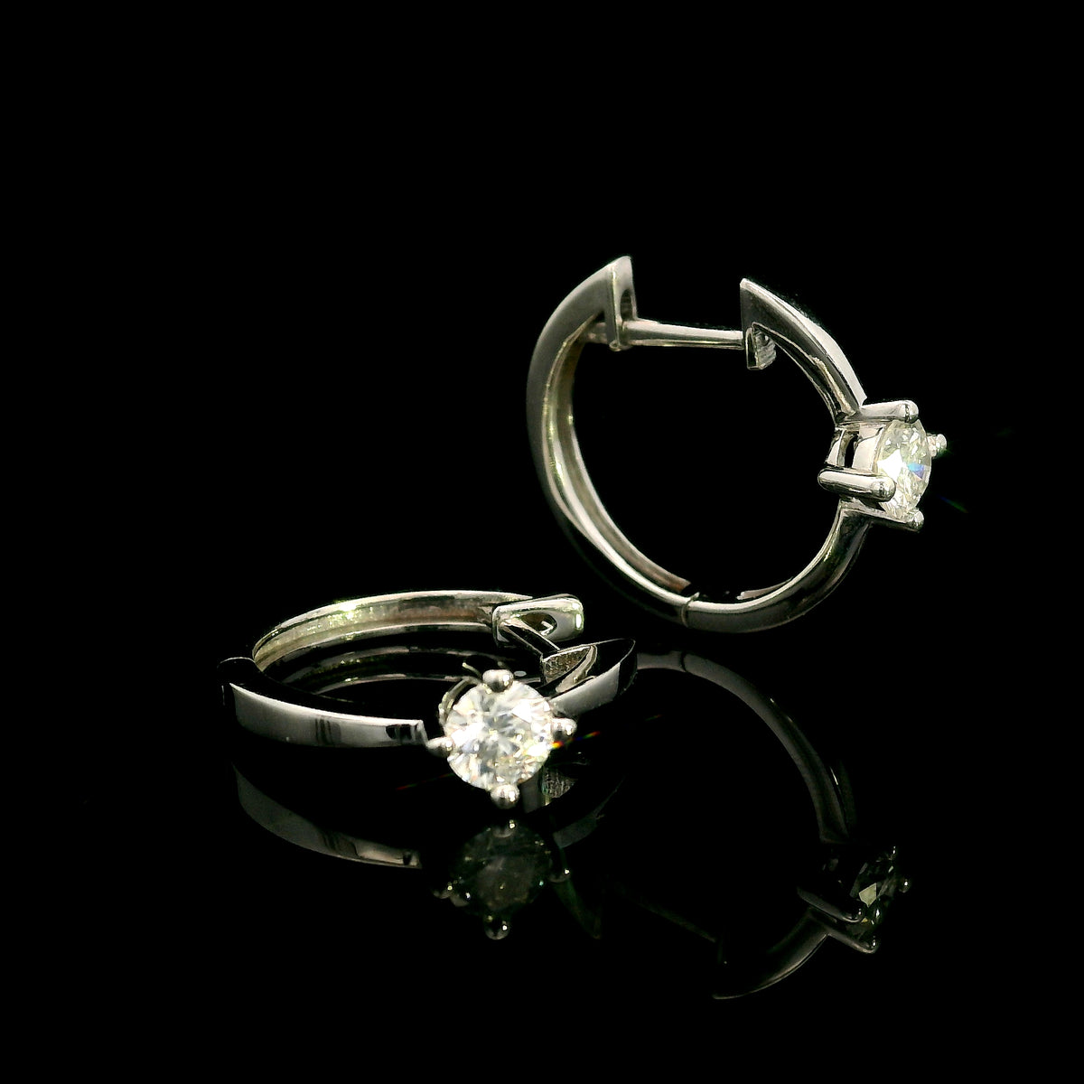 18K white gold huggie hoop earrings featuring a round diamond in a four-prong setting on each polished hoop.