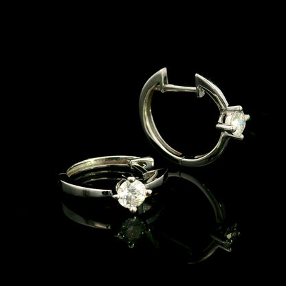 18K white gold huggie hoop earrings featuring a round diamond in a four-prong setting on each polished hoop.