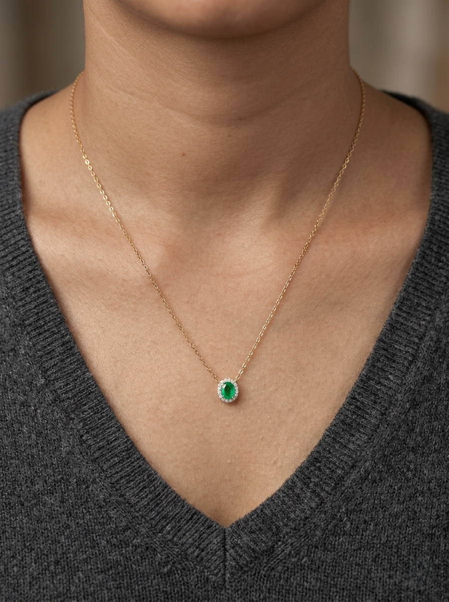 Emerald and diamond halo necklace in 18K yellow gold featuring 0.51 carat emerald and 0.10 carat diamonds by Emirates Diamonds.