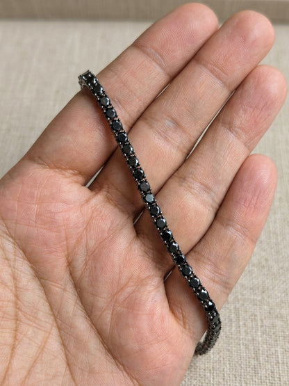 18K white gold black diamond tennis bracelet featuring a continuous row of round natural black diamonds totaling 8.38 carats