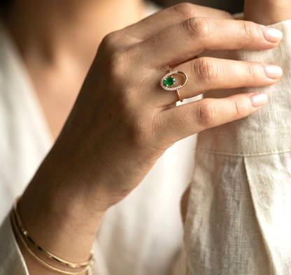 18K yellow gold emerald and diamond open halo ring with oval-cut emerald.