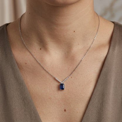 Blue sapphire and diamond necklace in 18K white gold featuring a rectangular emerald-cut sapphire suspended beneath a V-shaped row of round diamonds.