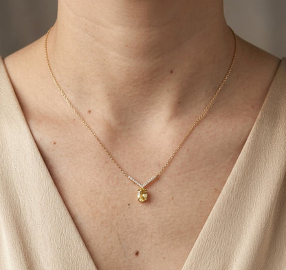 Yellow sapphire and diamond necklace in 18K yellow gold featuring a 1.01 carat oval yellow sapphire suspended beneath a V-shaped arrangement of round diamonds.