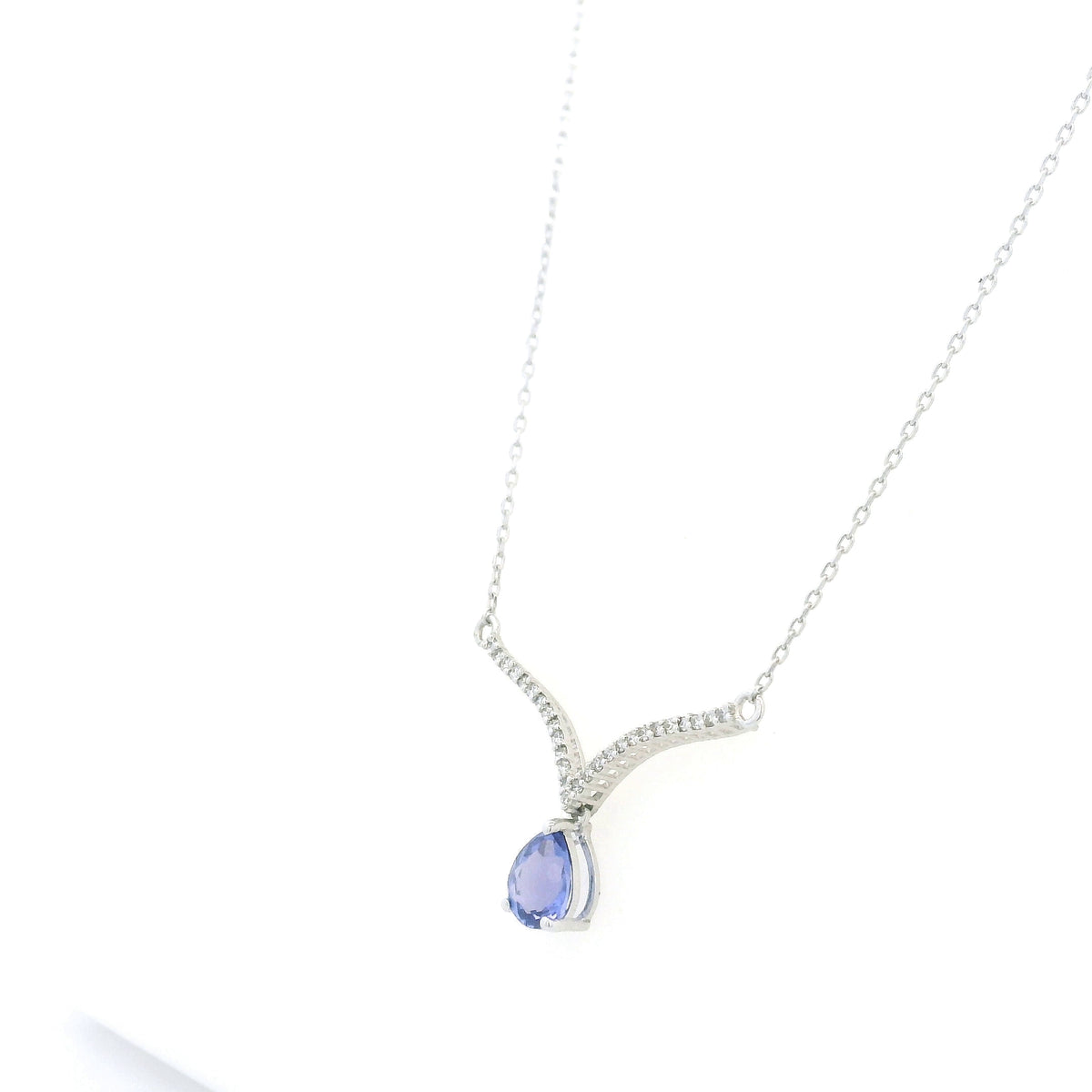 Pear shaped tanzanite and diamond necklace in 18K white gold featuring a blue-violet tanzanite drop suspended beneath two curved diamond-set bars forming a V-shaped design.