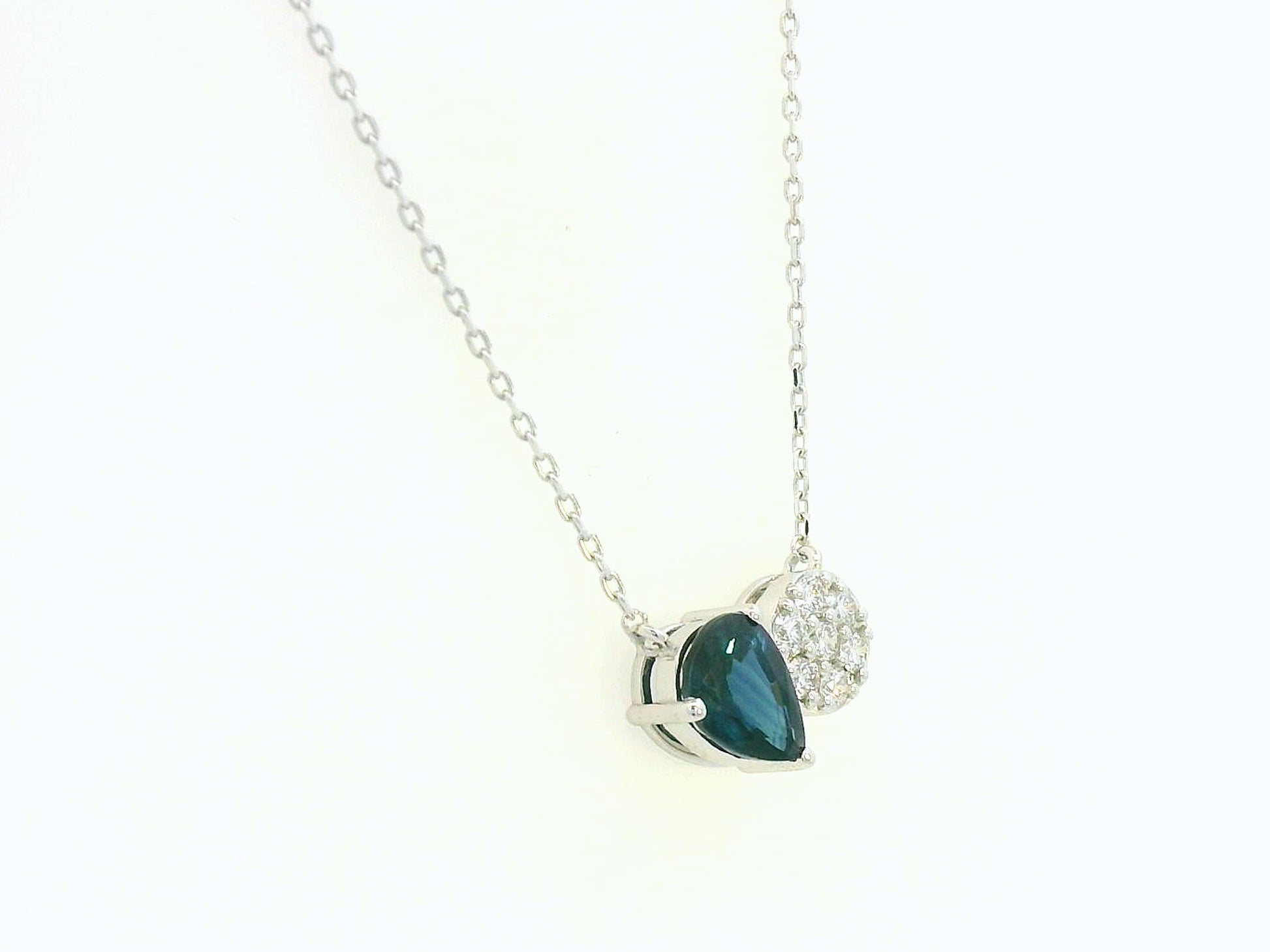 18K white gold pendant featuring a 0.97 carat pear-cut blue sapphire and 0.17 carat round diamond cluster on a fine gold chain.