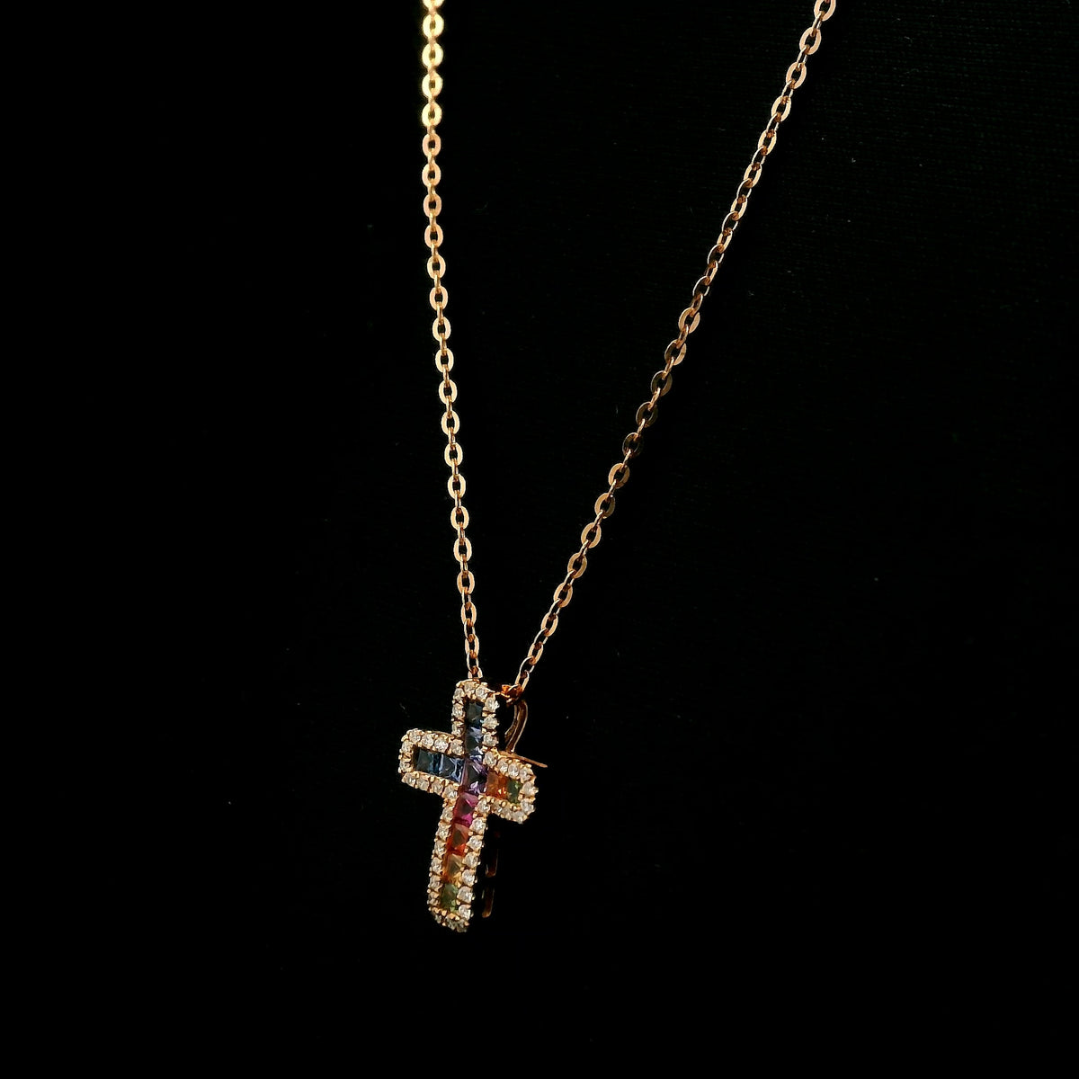 Multicolour sapphire and diamond cross necklace in 18K rose gold with colourful sapphires surrounded by round brilliant diamonds.
