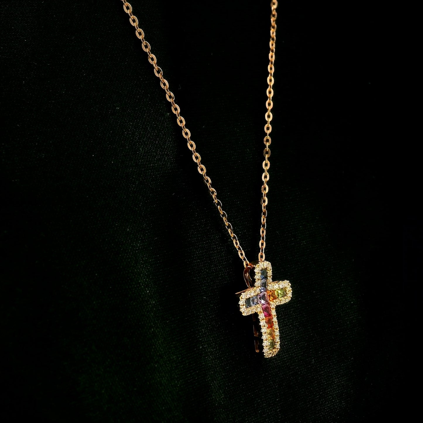 Multicolour sapphire and diamond cross necklace in 18K rose gold with colourful sapphires surrounded by round brilliant diamonds.