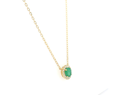 Emerald and diamond halo necklace in 18K yellow gold featuring 0.51 carat emerald and 0.10 carat diamonds by Emirates Diamonds.