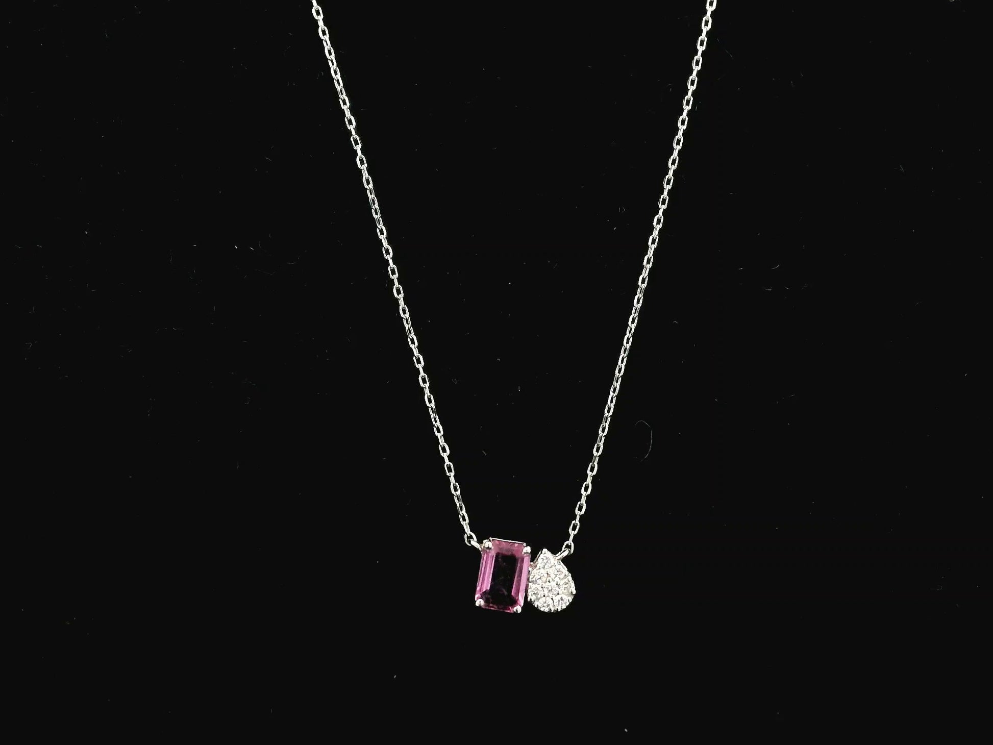 18K white gold pendant necklace featuring a 0.63 carat emerald cut pink sapphire paired with a 0.07 carat pear shaped diamond.