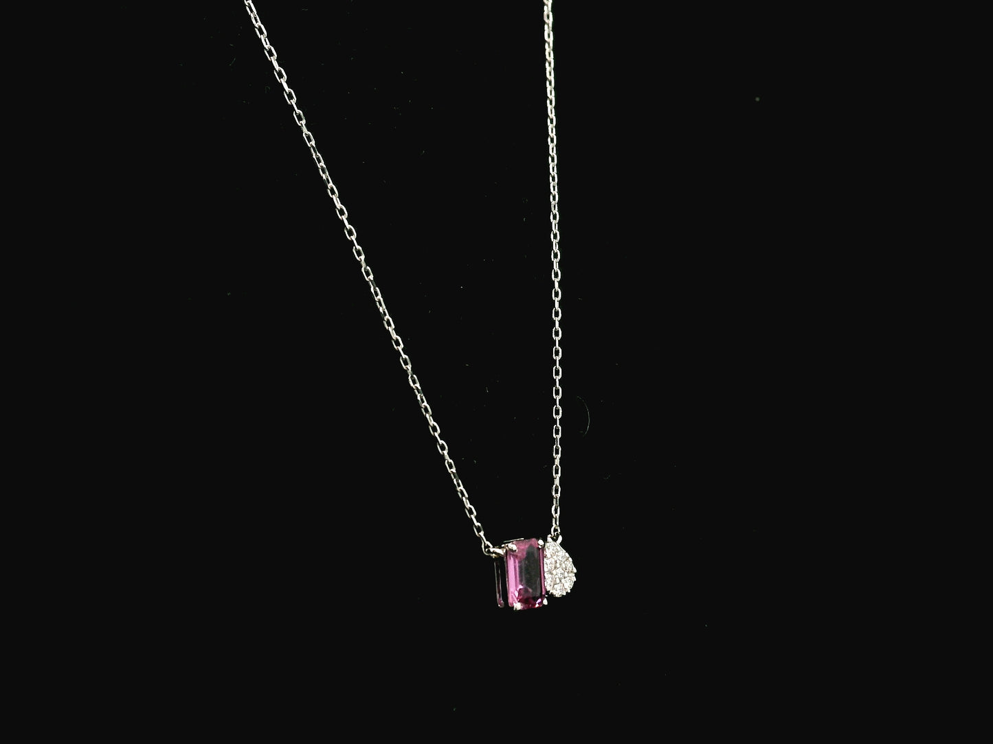 18K white gold pendant necklace featuring a 0.63 carat emerald cut pink sapphire paired with a 0.07 carat pear shaped diamond.