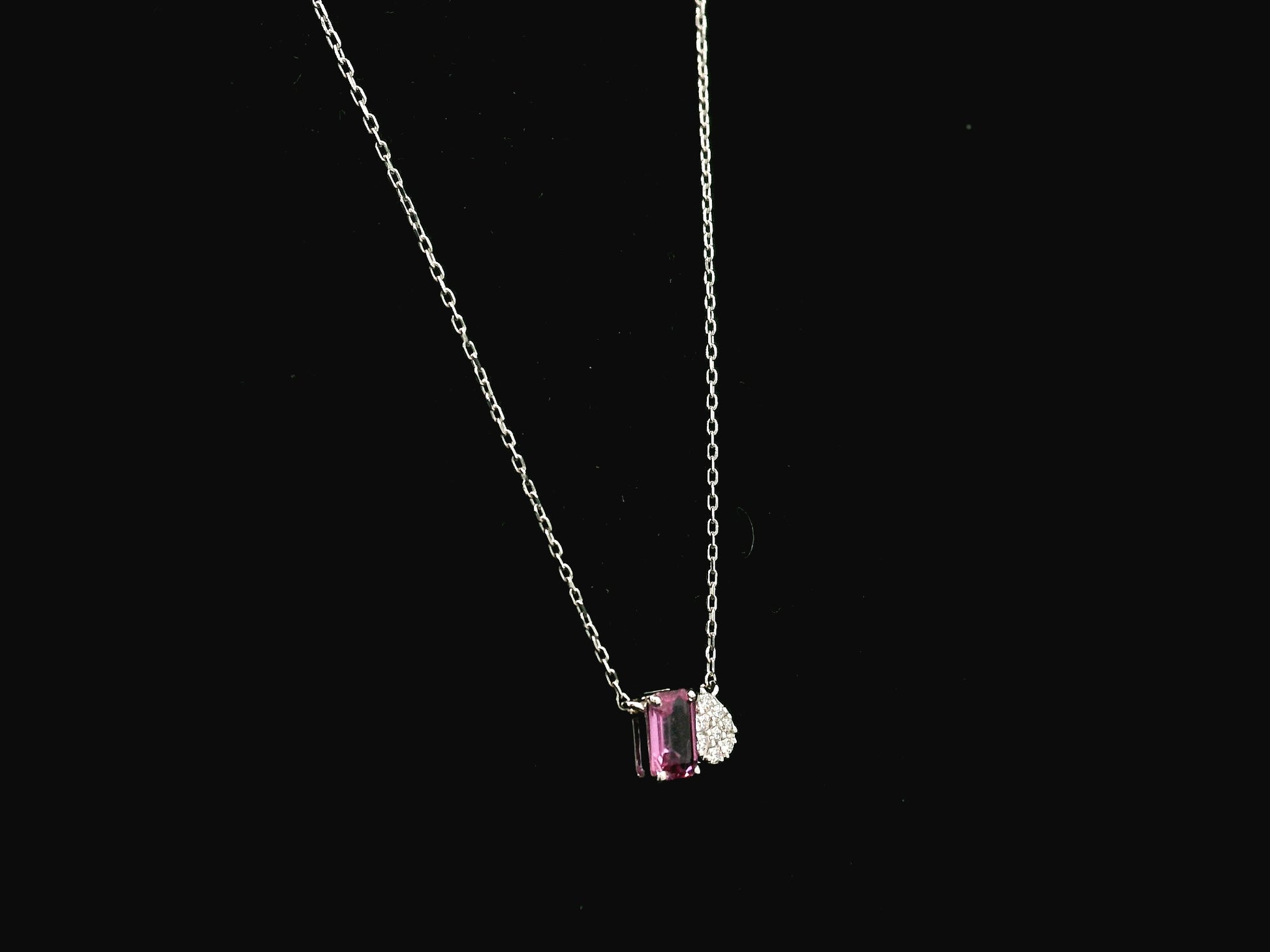 18K white gold pendant necklace featuring a 0.63 carat emerald cut pink sapphire paired with a 0.07 carat pear shaped diamond.