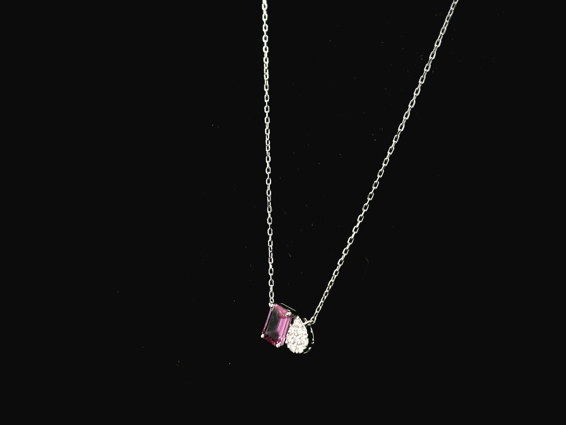 18K white gold pendant necklace featuring a 0.63 carat emerald cut pink sapphire paired with a 0.07 carat pear shaped diamond.