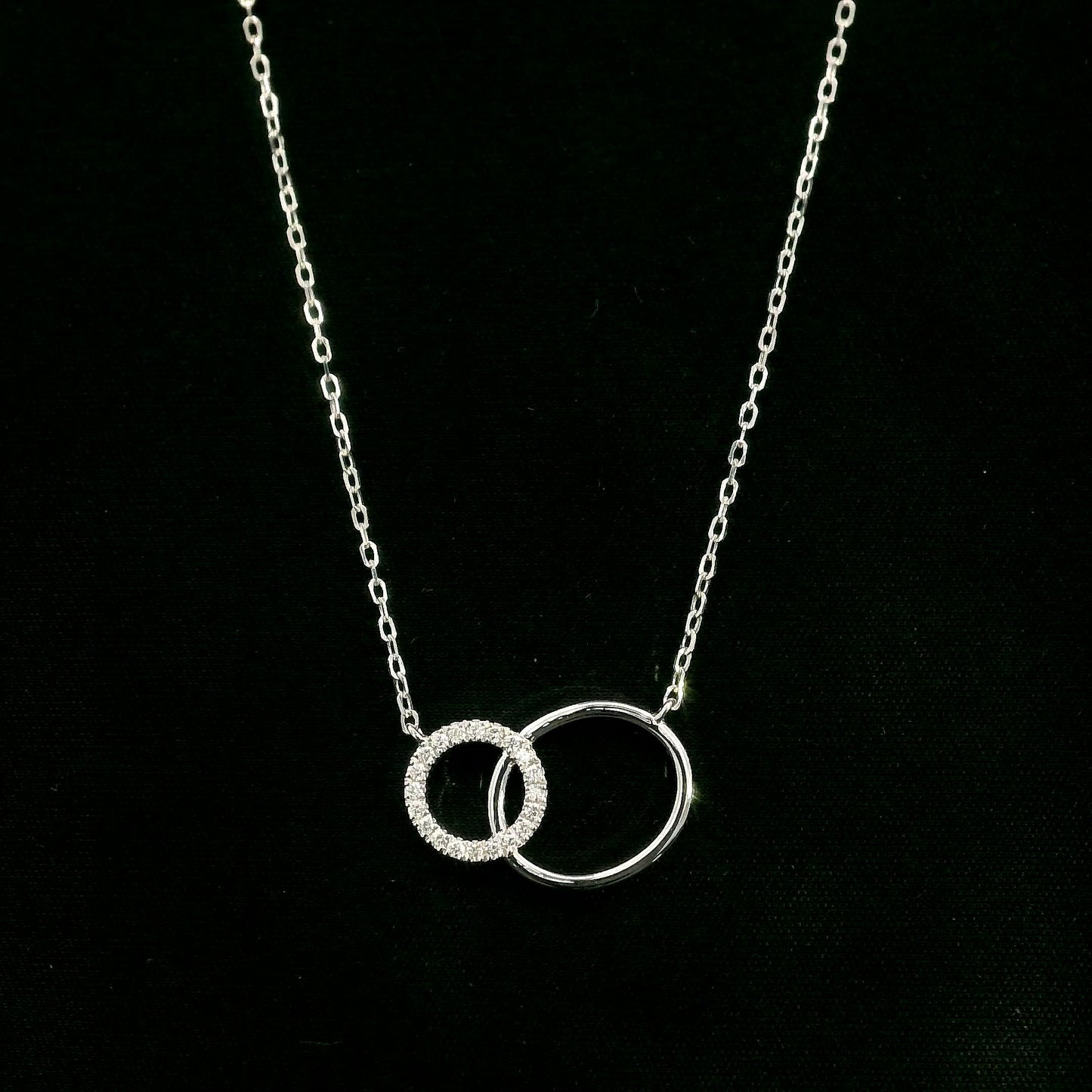 Interlocking circle diamond necklace in 18K white gold with one pavé diamond circle and one polished circle.