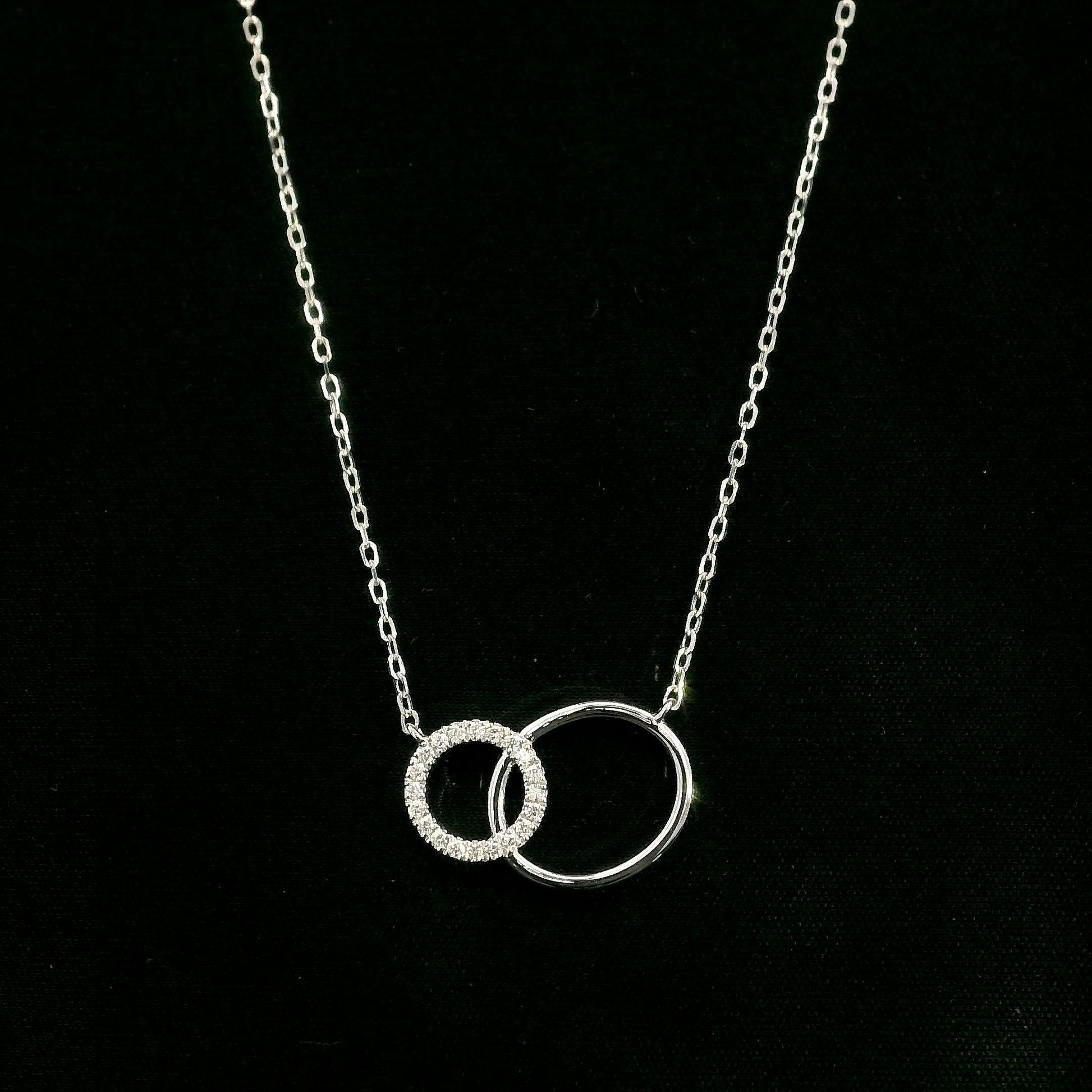 Interlocking circle diamond necklace in 18K white gold with one pavé diamond circle and one polished circle.