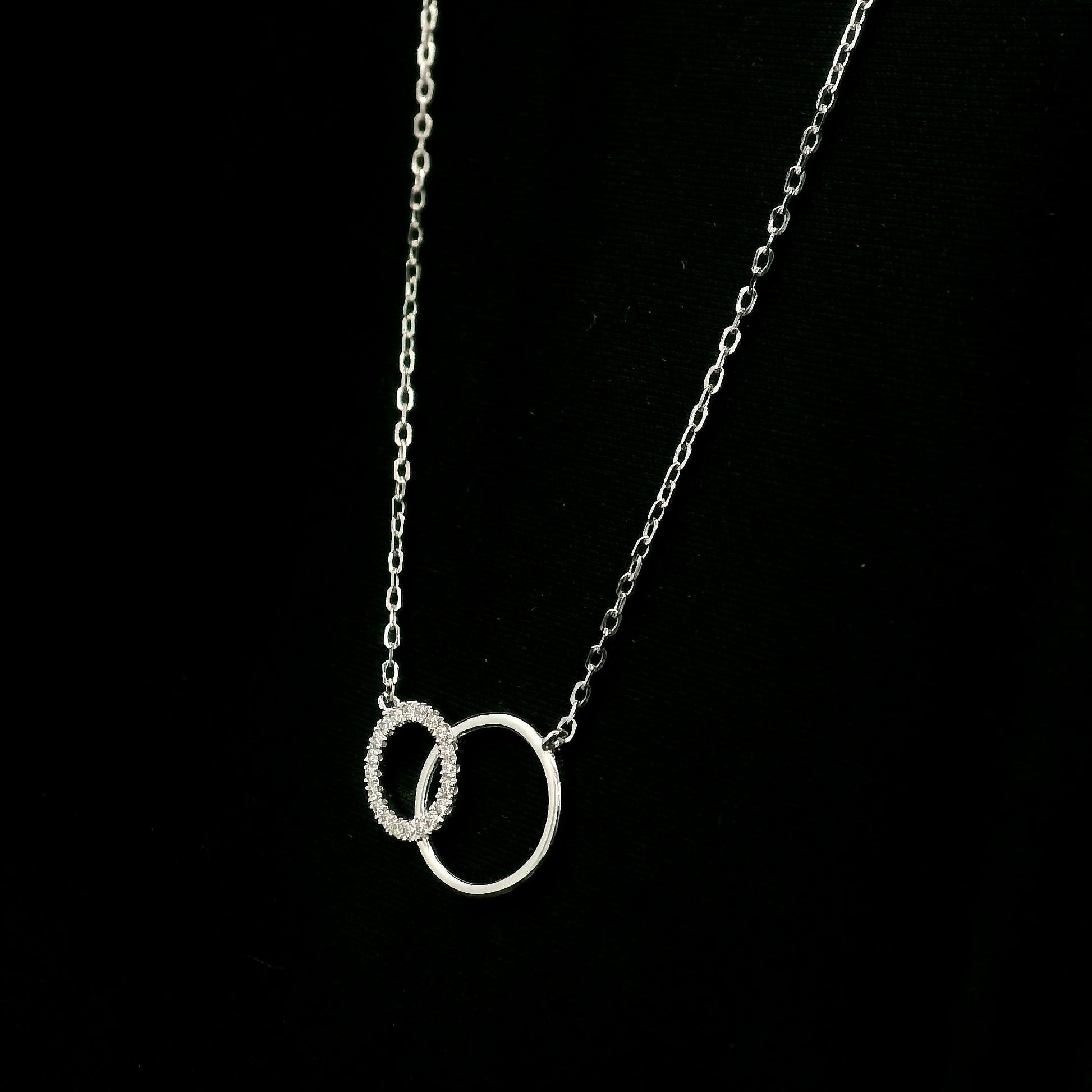 Interlocking circle diamond necklace in 18K white gold with one pavé diamond circle and one polished circle.