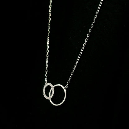 Interlocking circle diamond necklace in 18K white gold with one pavé diamond circle and one polished circle.