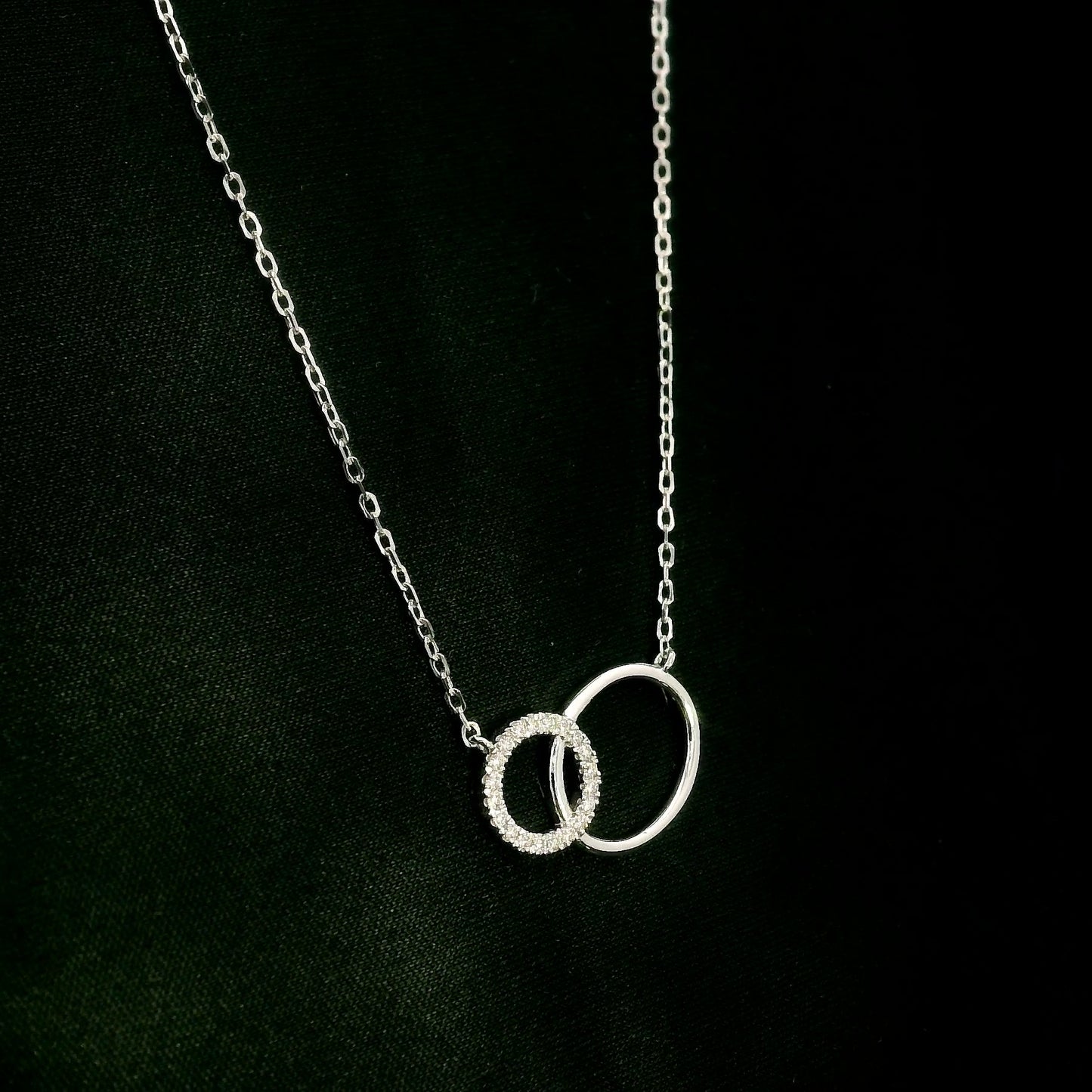 Interlocking circle diamond necklace in 18K white gold with one pavé diamond circle and one polished circle.