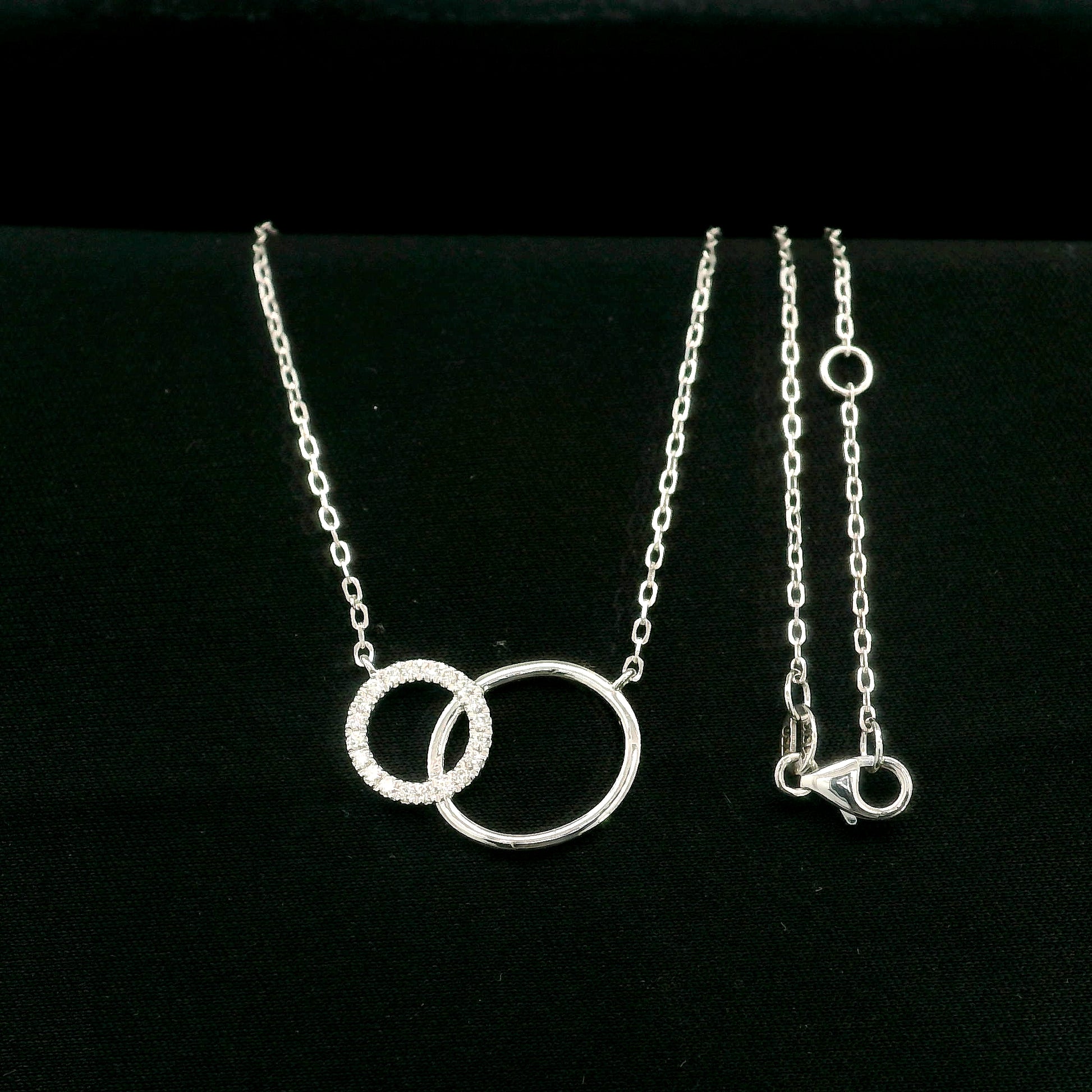 Interlocking circle diamond necklace in 18K white gold with one pavé diamond circle and one polished circle.