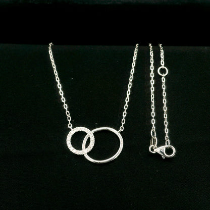 Interlocking circle diamond necklace in 18K white gold with one pavé diamond circle and one polished circle.