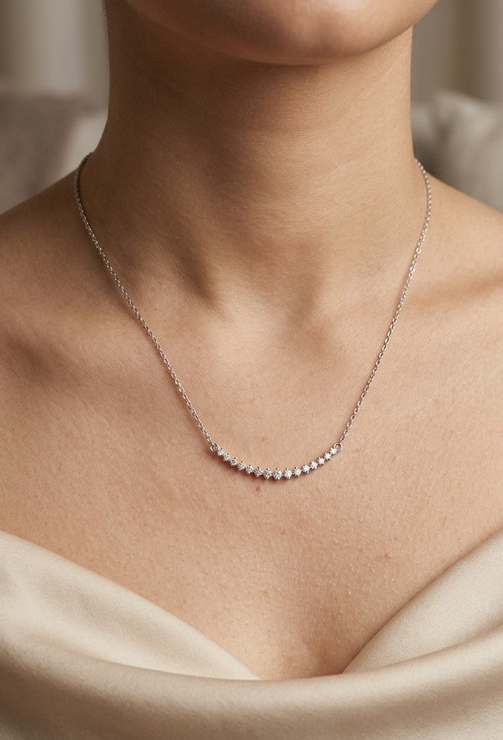 Diamond curved bar necklace in 18K white gold featuring a gently curved row of round diamonds with a total weight of 0.18 carat, connected to a fine white gold chain.