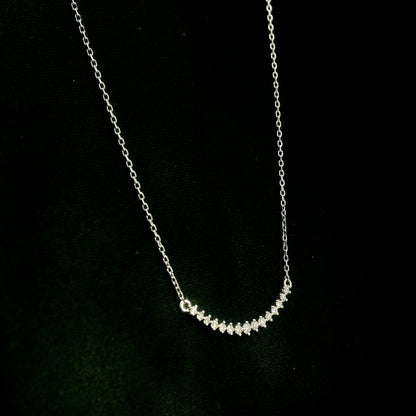 Diamond curved bar necklace in 18K white gold featuring a gently curved row of round diamonds with a total weight of 0.18 carat, connected to a fine white gold chain.