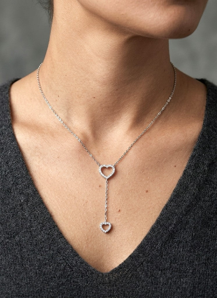 Diamond double heart Y necklace in 18K white gold featuring a larger open diamond heart at the neckline and a smaller diamond heart suspended from a delicate vertical drop chain, with 0.23 carat total diamond weight.