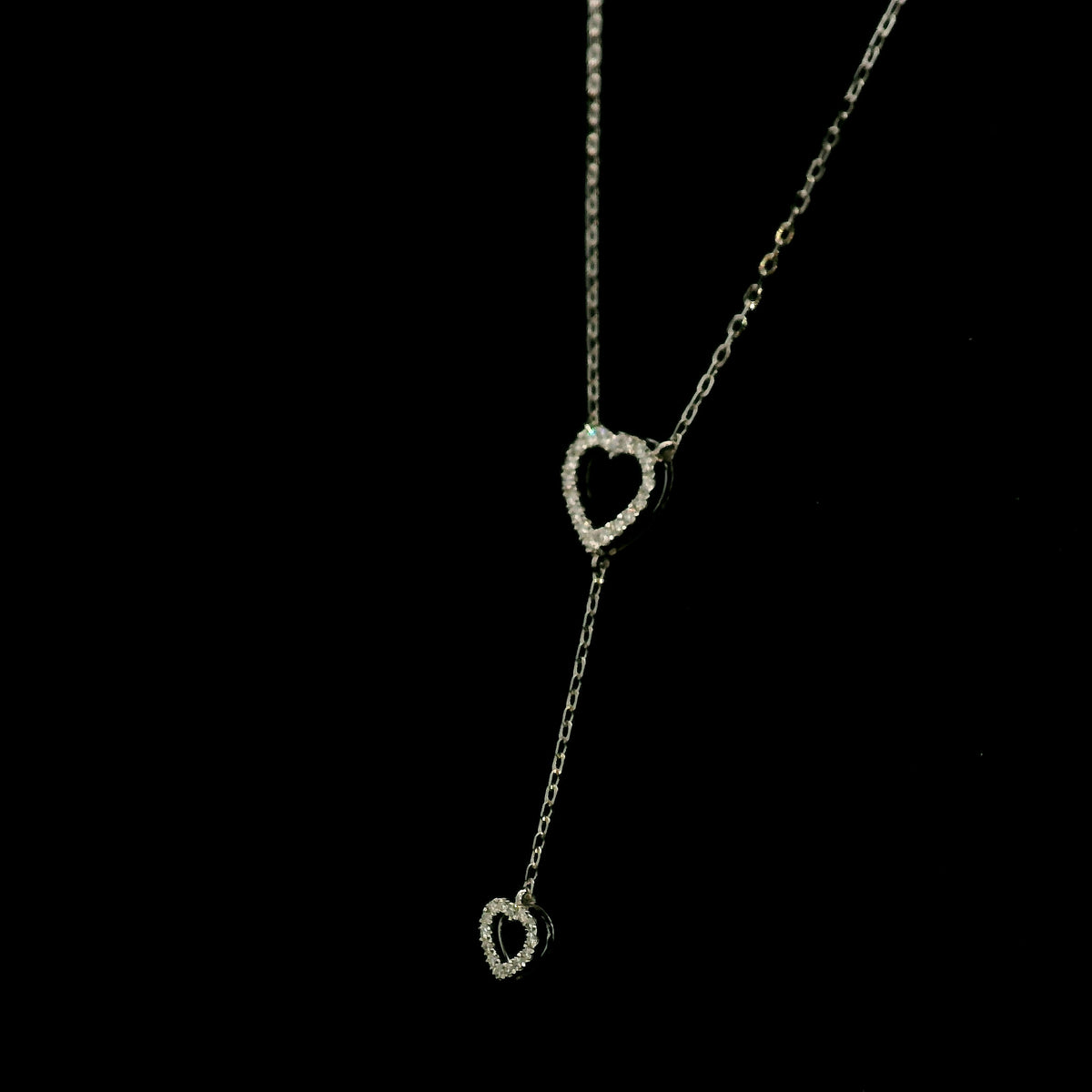 Diamond double heart Y necklace in 18K white gold featuring a larger open diamond heart at the neckline and a smaller diamond heart suspended from a delicate vertical drop chain, with 0.23 carat total diamond weight.