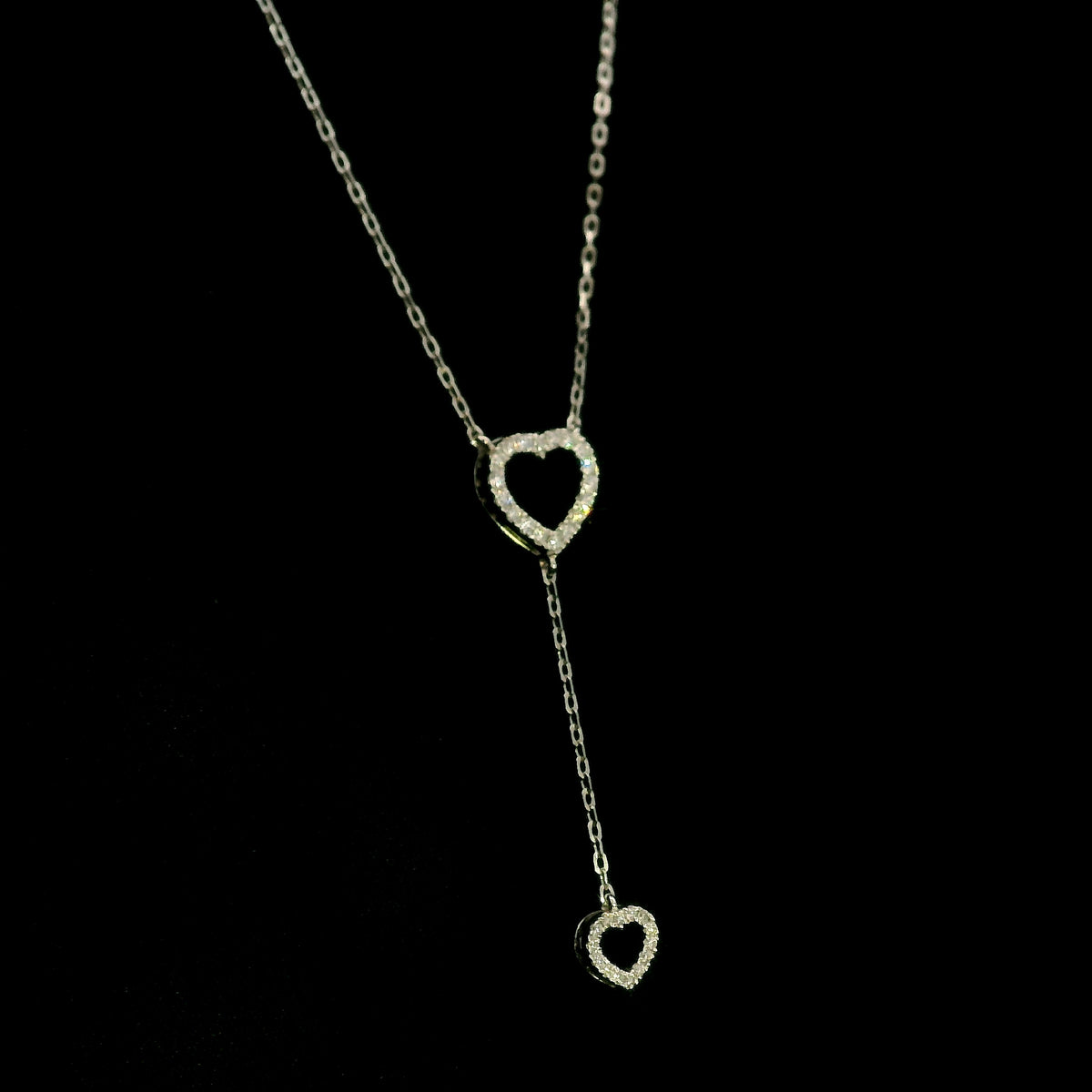 Diamond double heart Y necklace in 18K white gold featuring a larger open diamond heart at the neckline and a smaller diamond heart suspended from a delicate vertical drop chain, with 0.23 carat total diamond weight.