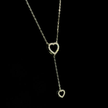 Diamond double heart Y necklace in 18K white gold featuring a larger open diamond heart at the neckline and a smaller diamond heart suspended from a delicate vertical drop chain, with 0.23 carat total diamond weight.