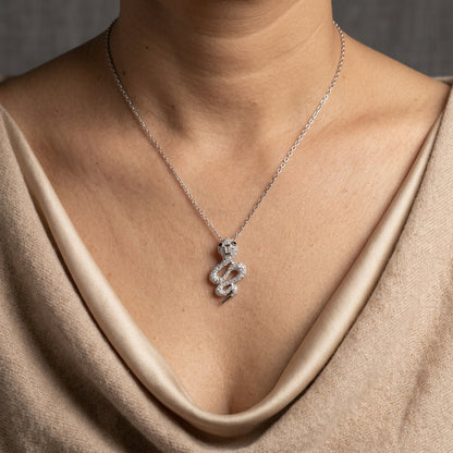 18K white gold snake pendant necklace featuring a curved serpent with round diamonds along its coiled body, a detailed head and a polished tapered tail.