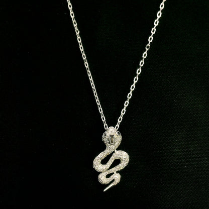 18K white gold snake pendant necklace featuring a curved serpent with round diamonds along its coiled body, a detailed head and a polished tapered tail.