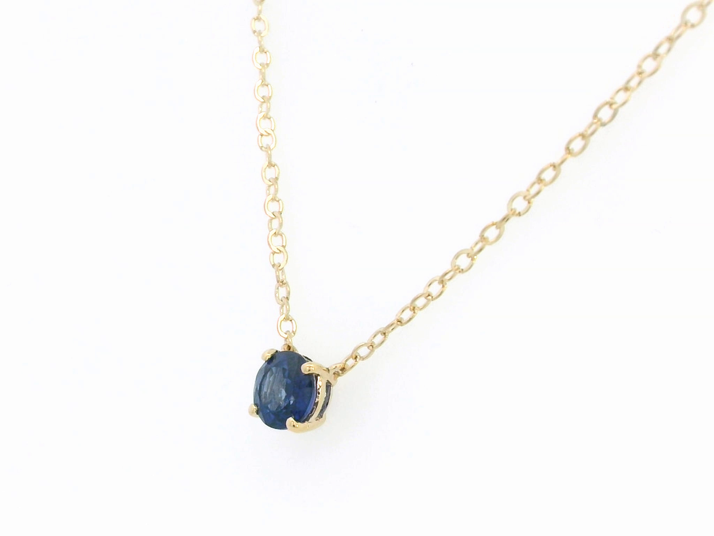 18K gold necklace featuring a round 0.89 carat blue sapphire pendant on a fine gold cable chain. Minimalist design with timeless elegance.

