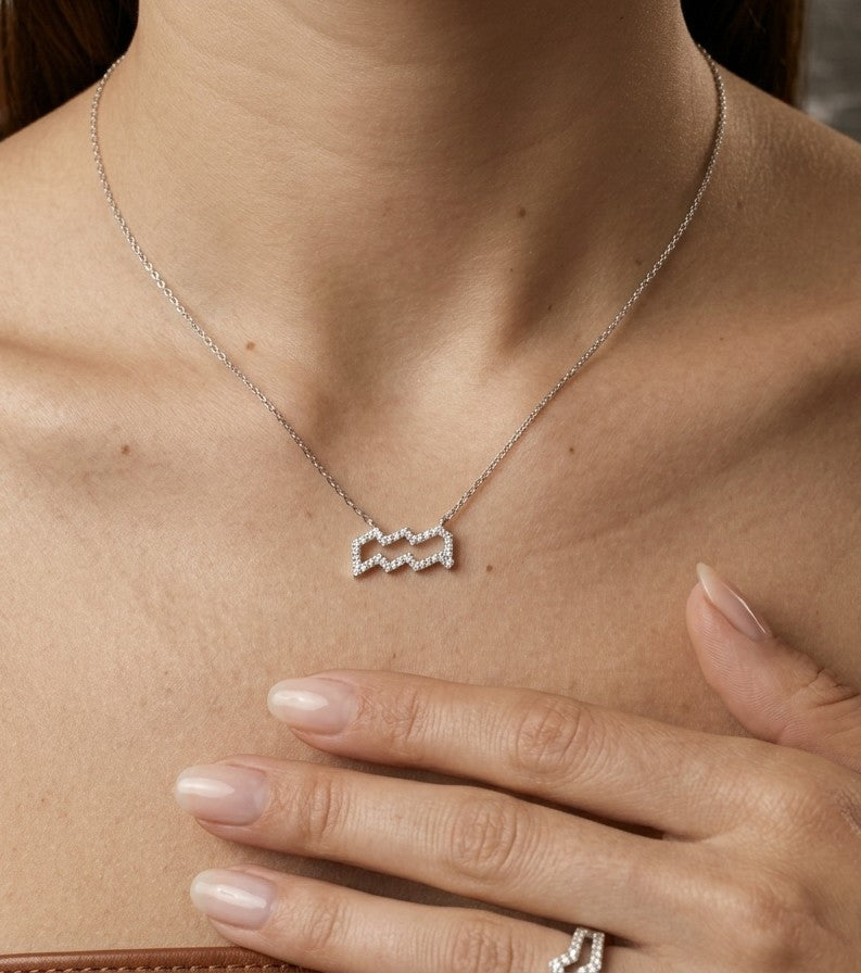 Aquarius zodiac necklace in 18K white gold with natural diamonds outlining the double zigzag Aquarius symbol, suspended from a delicate chain.