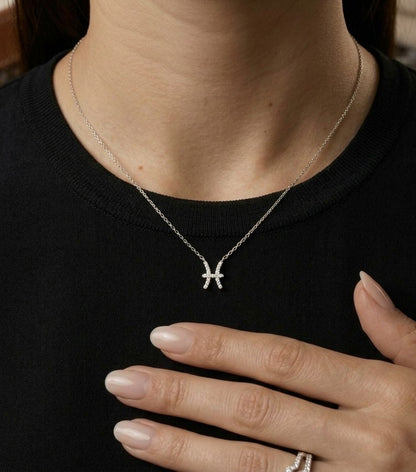 Pisces zodiac necklace in 18K white gold with natural diamonds outlining the Pisces symbol, featuring two curved lines joined at the centre and suspended from a chain.