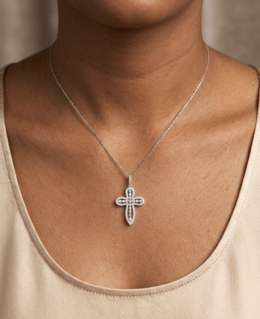 Openwork diamond cross pendant in 18K white gold with round diamond borders, central diamond accents and a diamond-set bail, displayed on a chain.