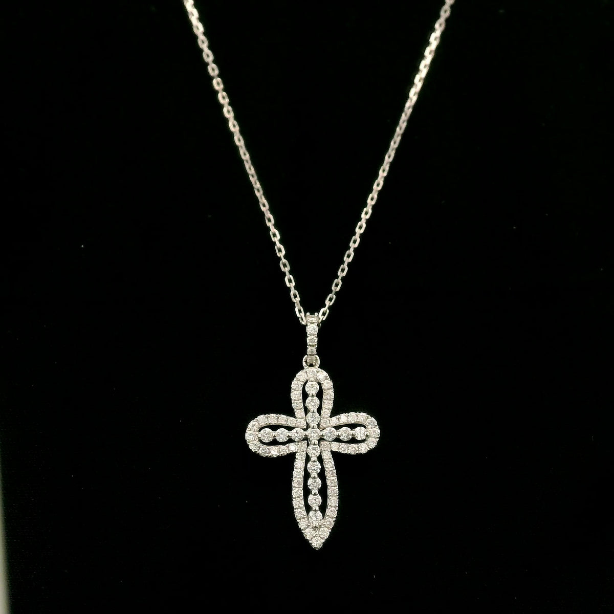 Openwork diamond cross pendant in 18K white gold with round diamond borders, central diamond accents and a diamond-set bail, displayed on a chain.