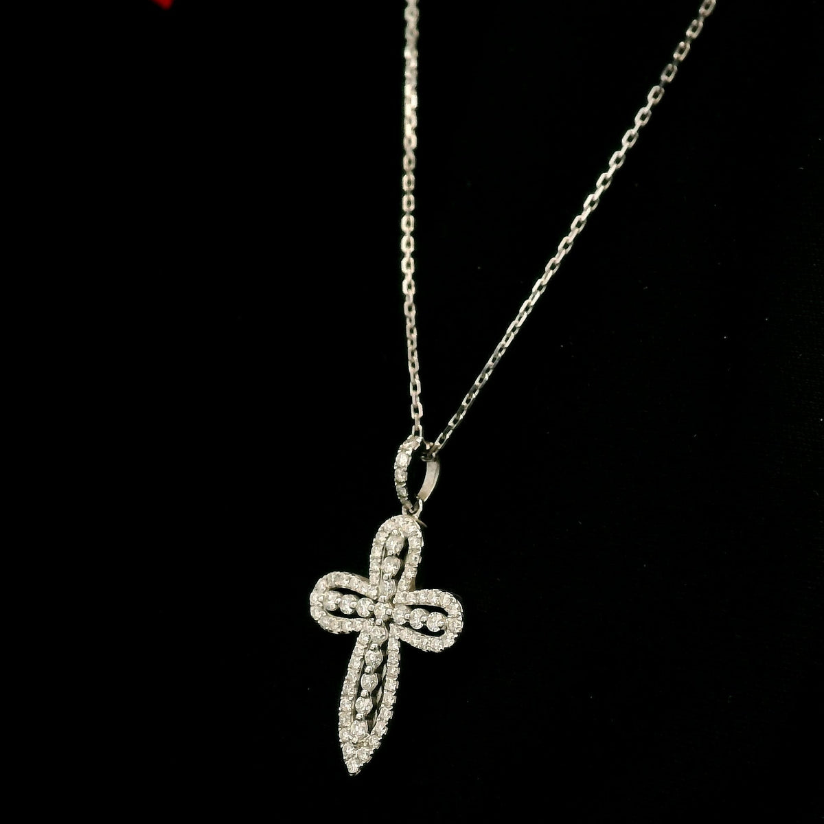 Openwork diamond cross pendant in 18K white gold with round diamond borders, central diamond accents and a diamond-set bail, displayed on a chain.