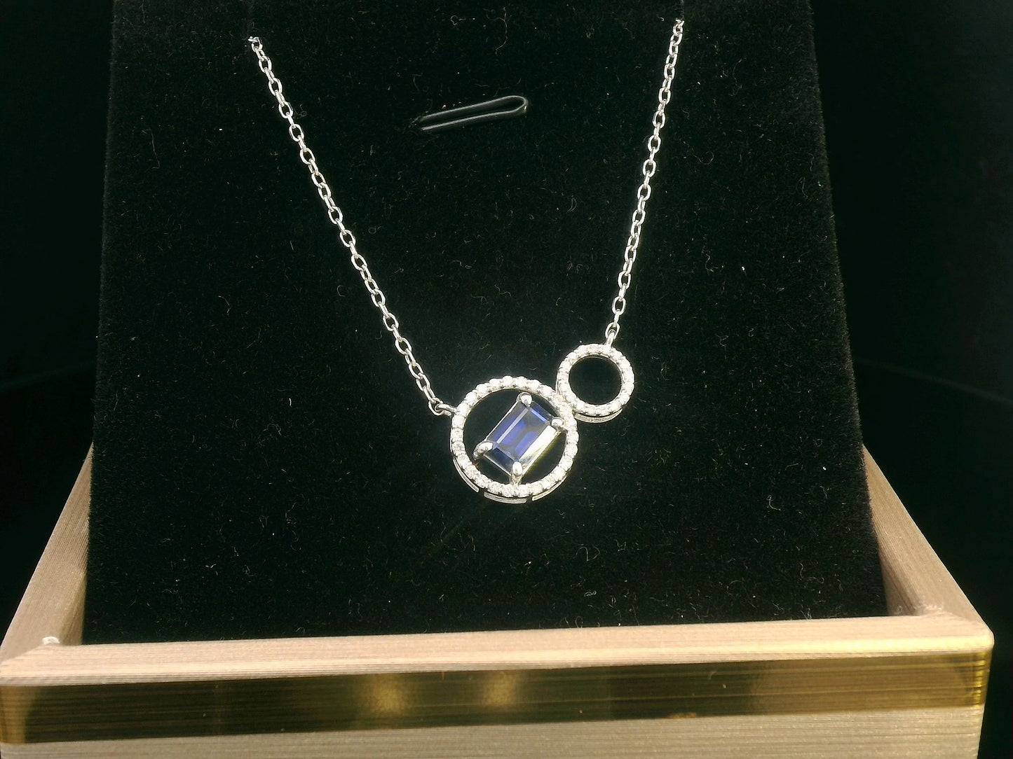 18K white gold necklace featuring a 0.65 CT emerald-cut sapphire with a 0.15 CT diamond halo, designed with a unique double-circle pendant for a sophisticated, modern look.